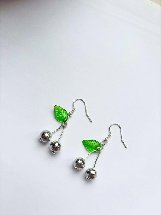 Pair of earrings with green leaf and silver bead designs on a white background
